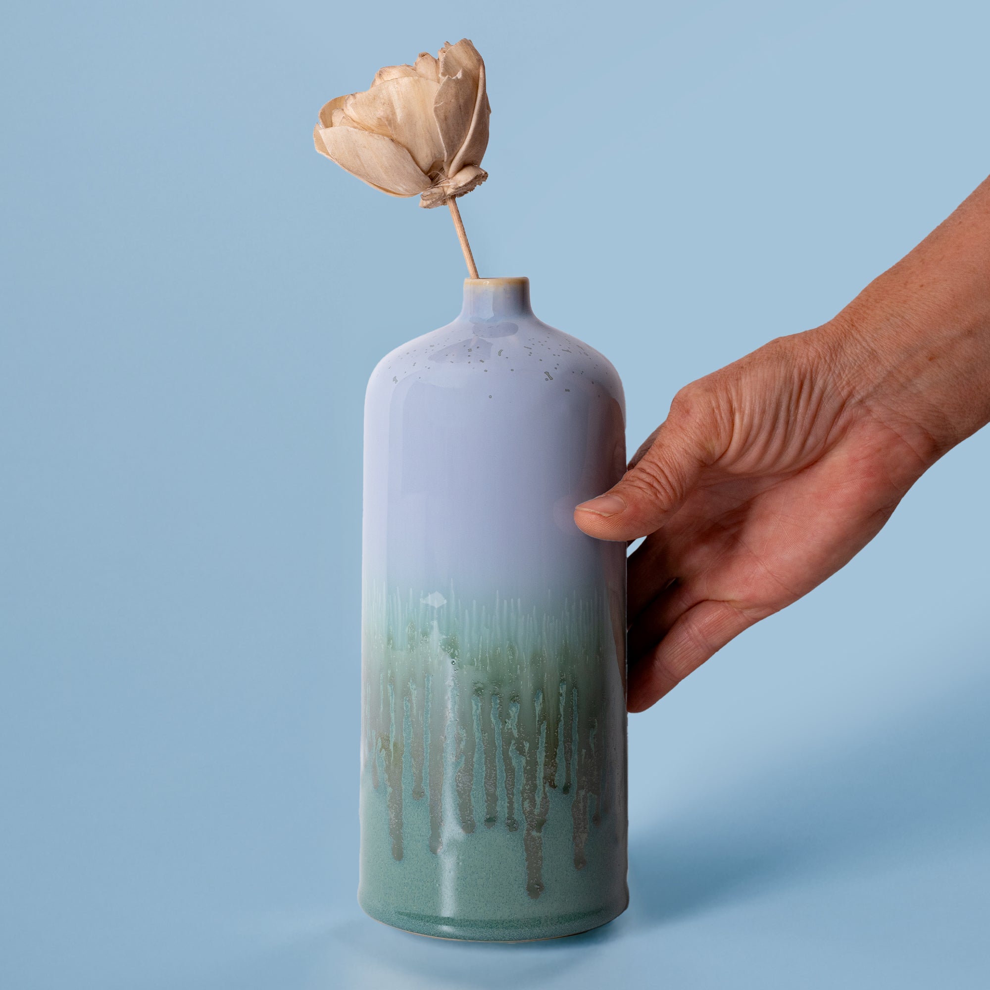 Pottery For The Planet medium decorative bud vase in lavender and green held by hand with dried flower