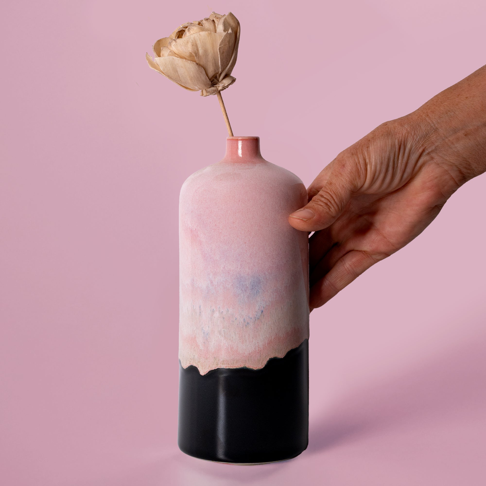 Pottery For The Planet medium decorative bud vase in pink and black held by hand with dried flower