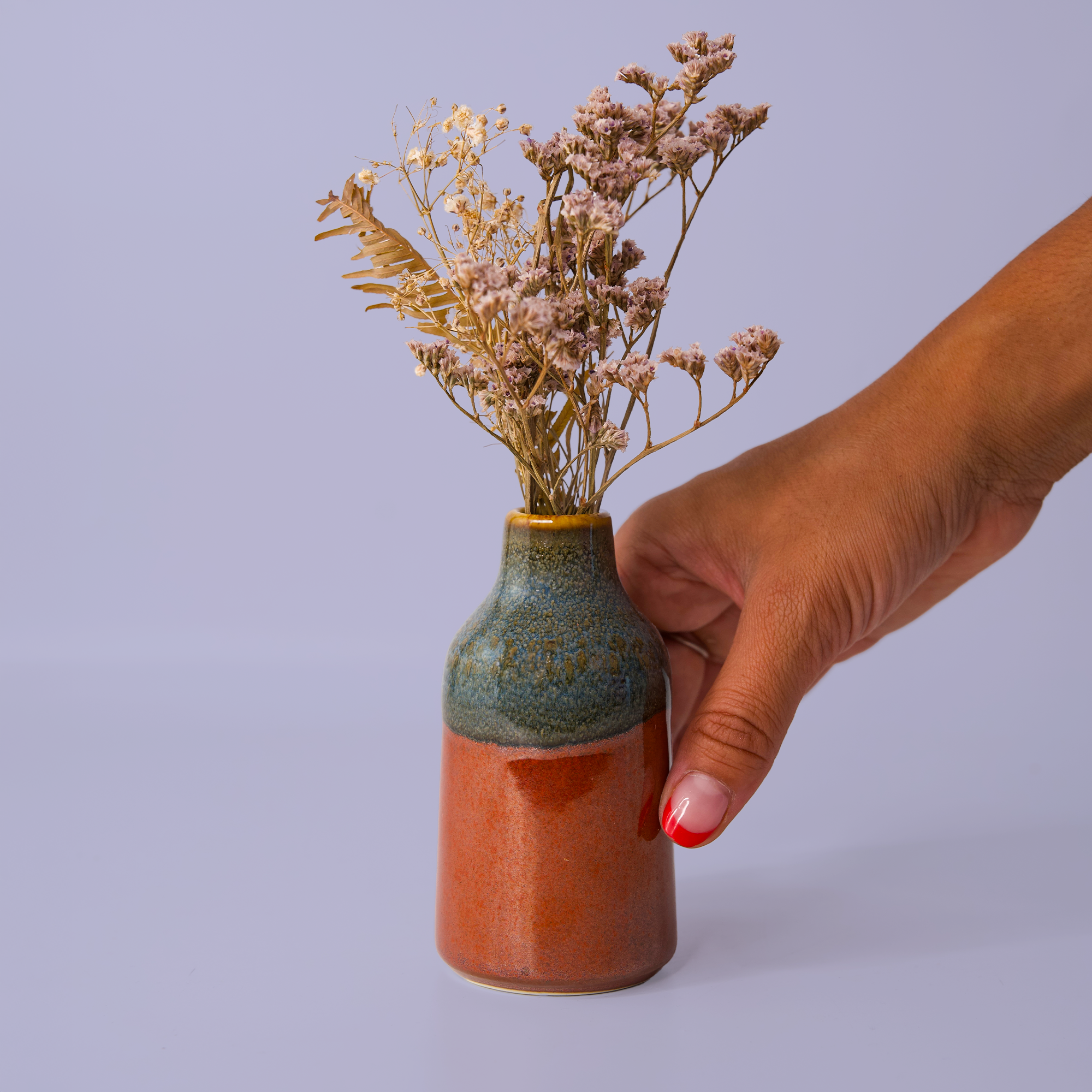 Hand holding a modern decorative flower vase with dried flowers by Pottery For The Planet