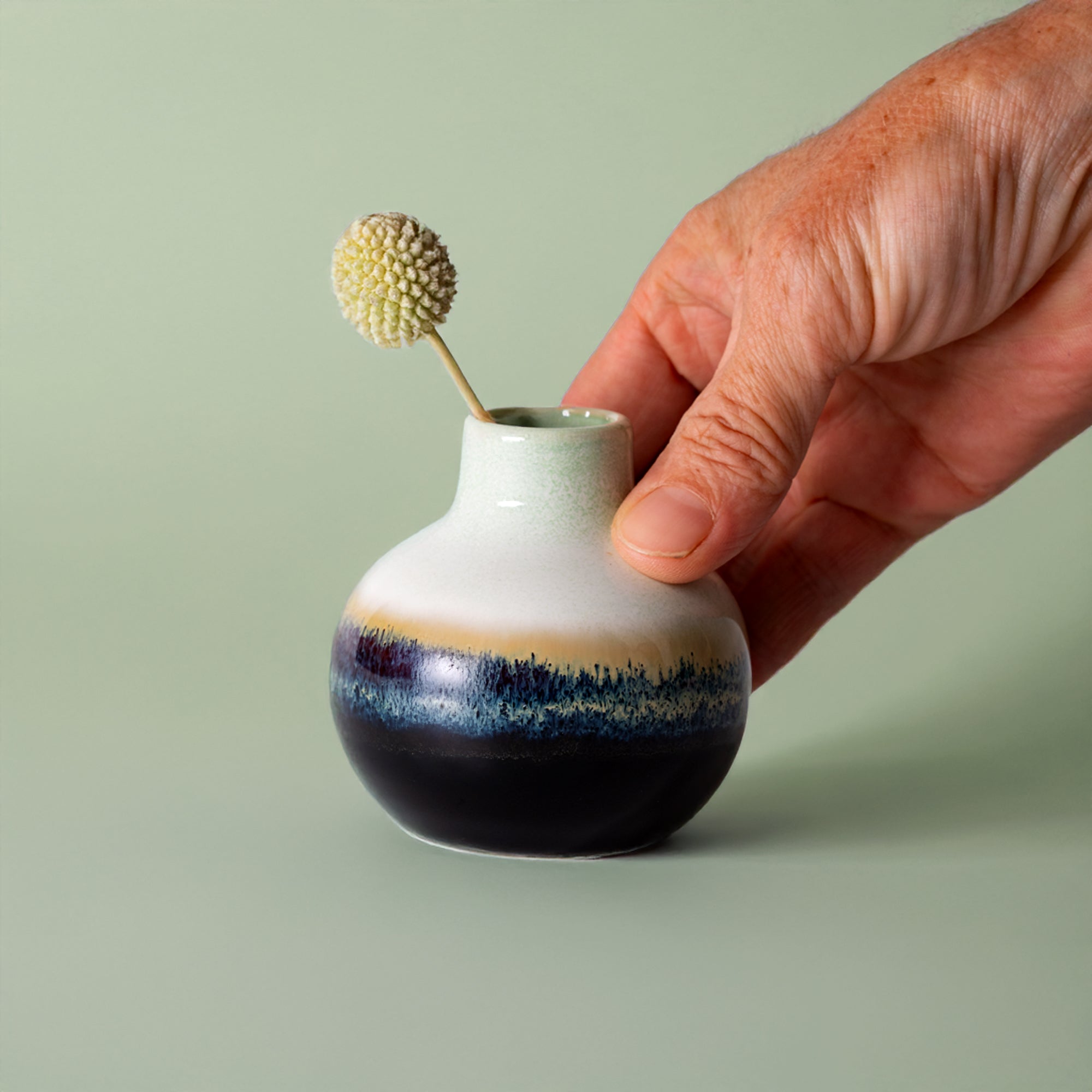 Small handmade home decor vase by Pottery For The Planet with gradient blue and white glaze held by hand