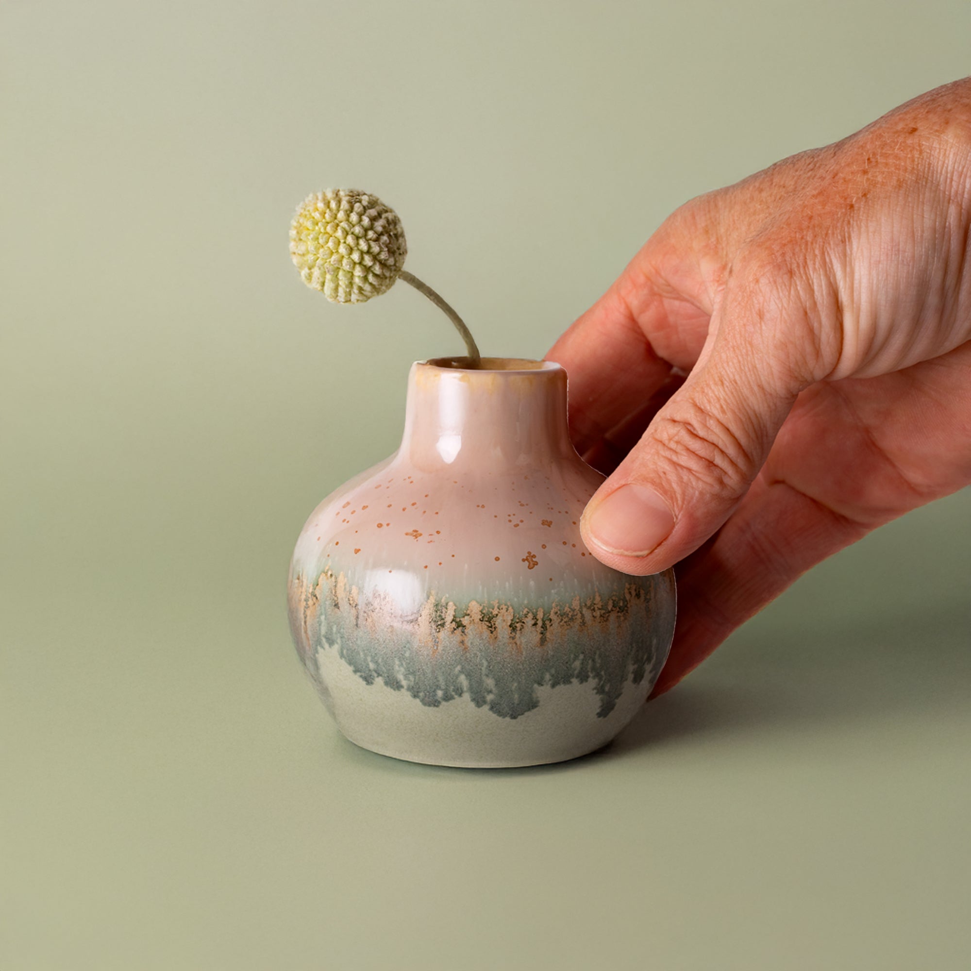 Small handmade home decor vase by Pottery For The Planet held next to a dried flower