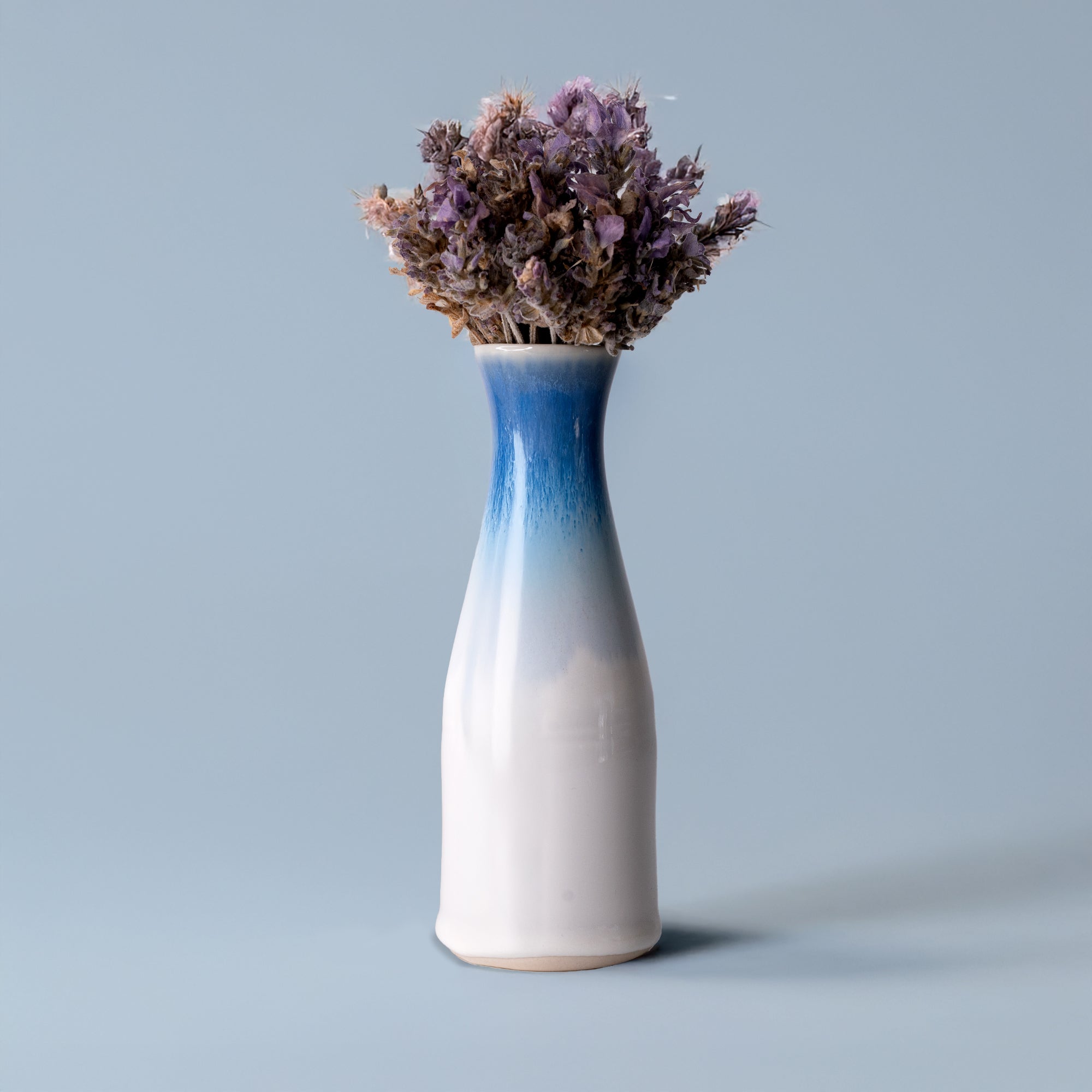 Unique ceramic flower vase with blue gradient design holding dried purple flowers from Pottery For The Planet