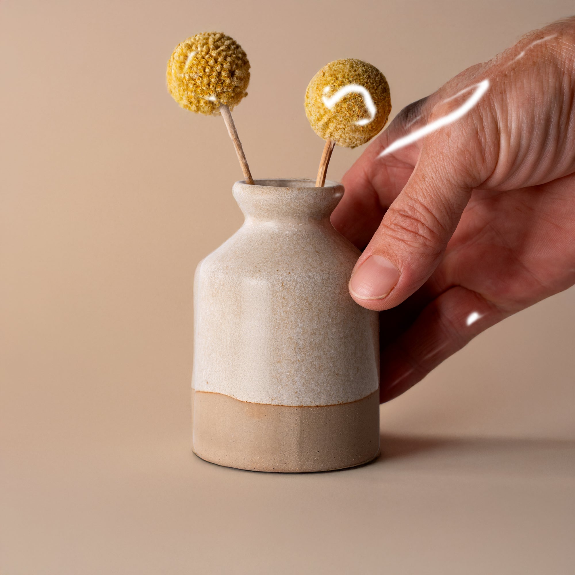 Miniature decorative vase for shelf by Pottery For The Planet with beige two-tone design held by hand