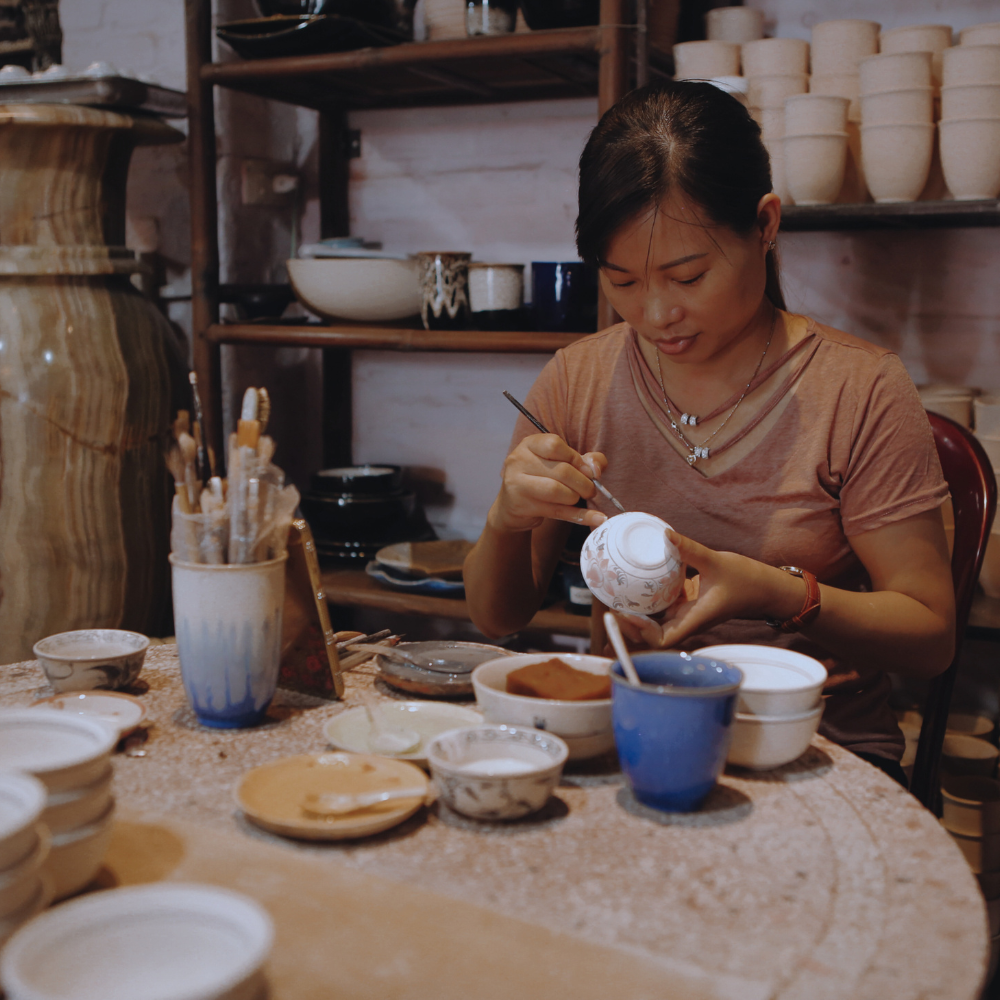 Woman SIt At Table Hand Painting On Ceramic Travel Cup