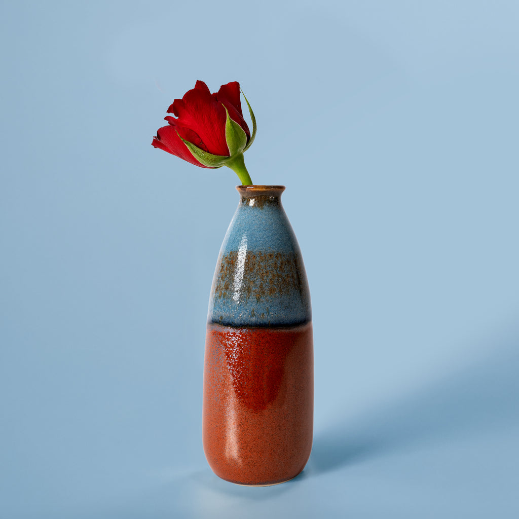 Pottery For The Planet artisan decorative vase for flowers with blue and red glaze holding a single red flower