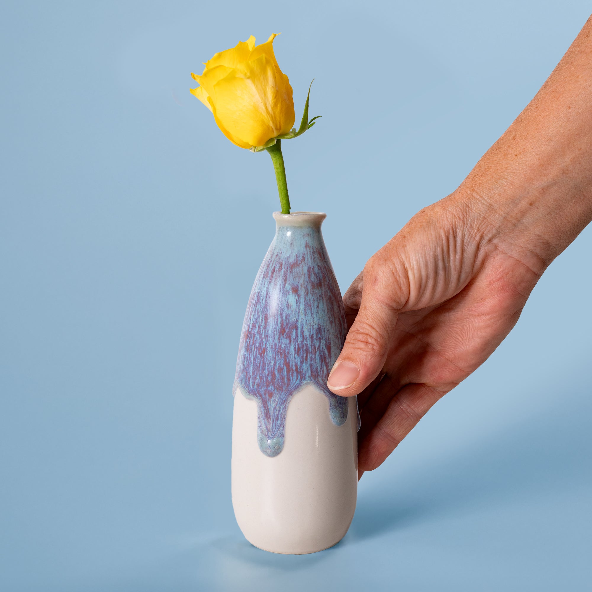 Hand holding artisan decorative vase for flowers with yellow rose by Pottery For The Planet