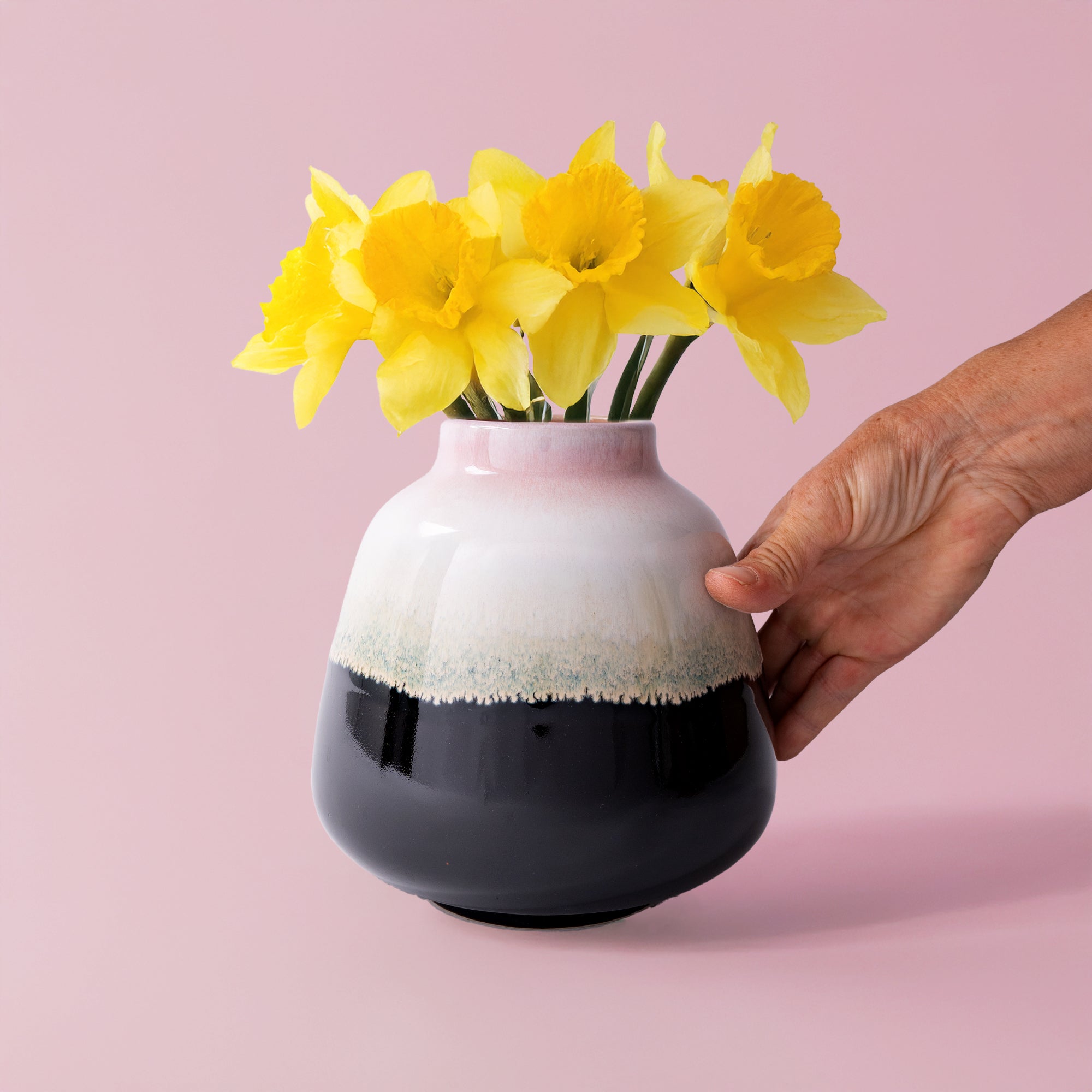 Pottery For The Planet bouquet vase for home decor with yellow daffodils and hand on pink background