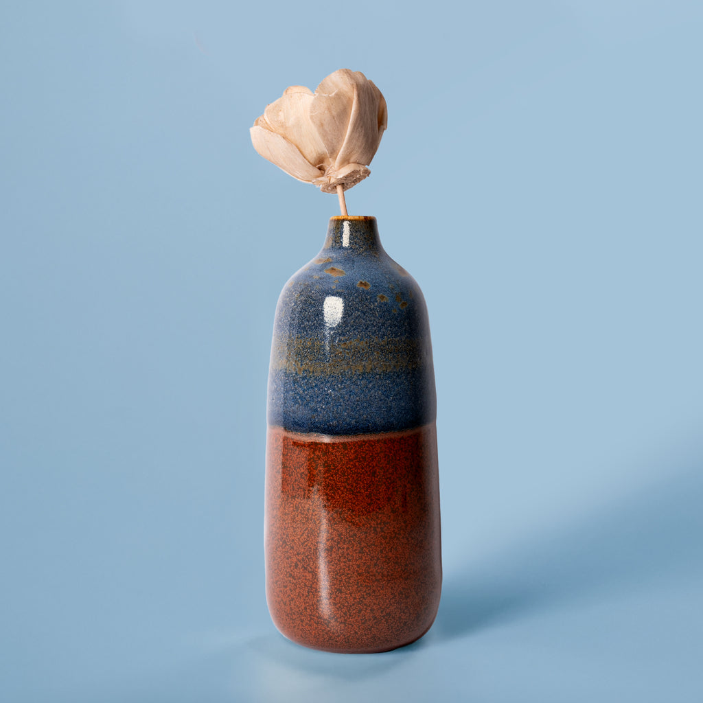Pottery For The Planet eco-friendly home decor vase with blue and brown glaze holding a dried flower