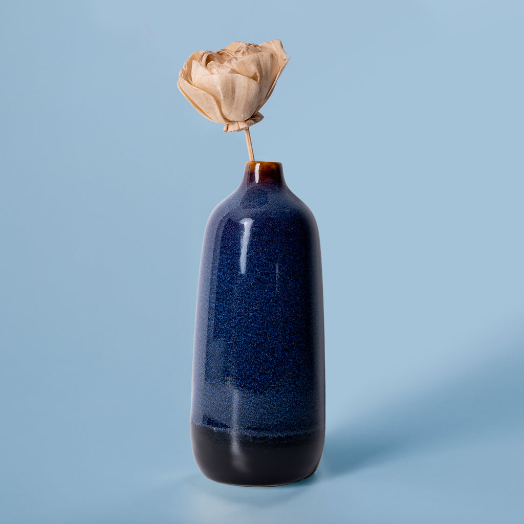 Pottery For The Planet eco-friendly home decor vase in blue with a dried flower on light blue background