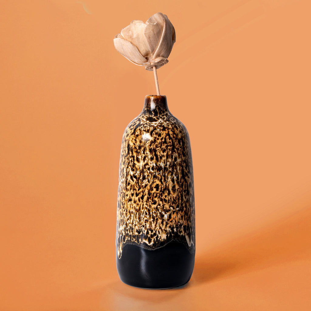 Pottery For The Planet eco-friendly home decor vase with textured brown and black glaze holding a dried flower