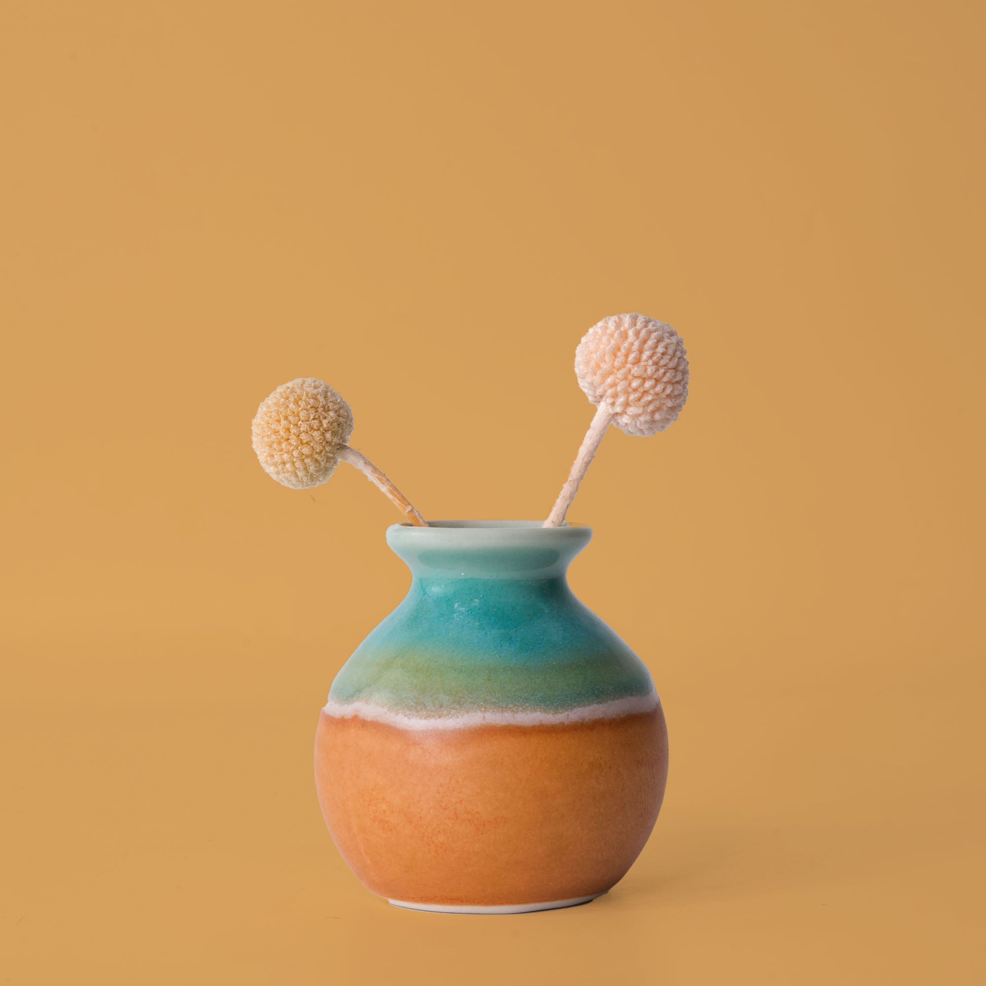 Pottery For The Planet eco-friendly home decor vase with blue and orange glaze holding dried flowers