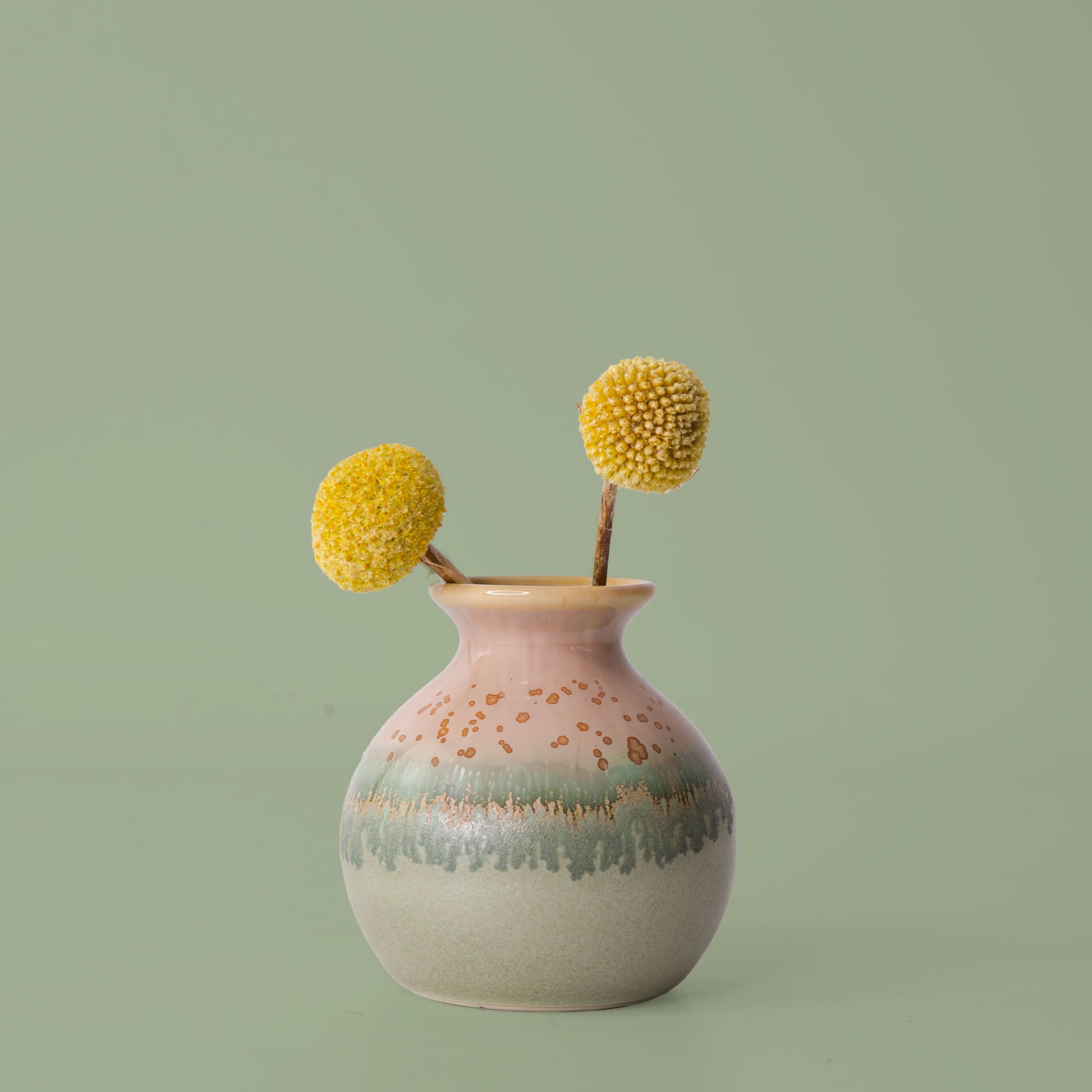 Pottery For The Planet eco-friendly home decor vase with pink and green glaze holding yellow billy ball flowers