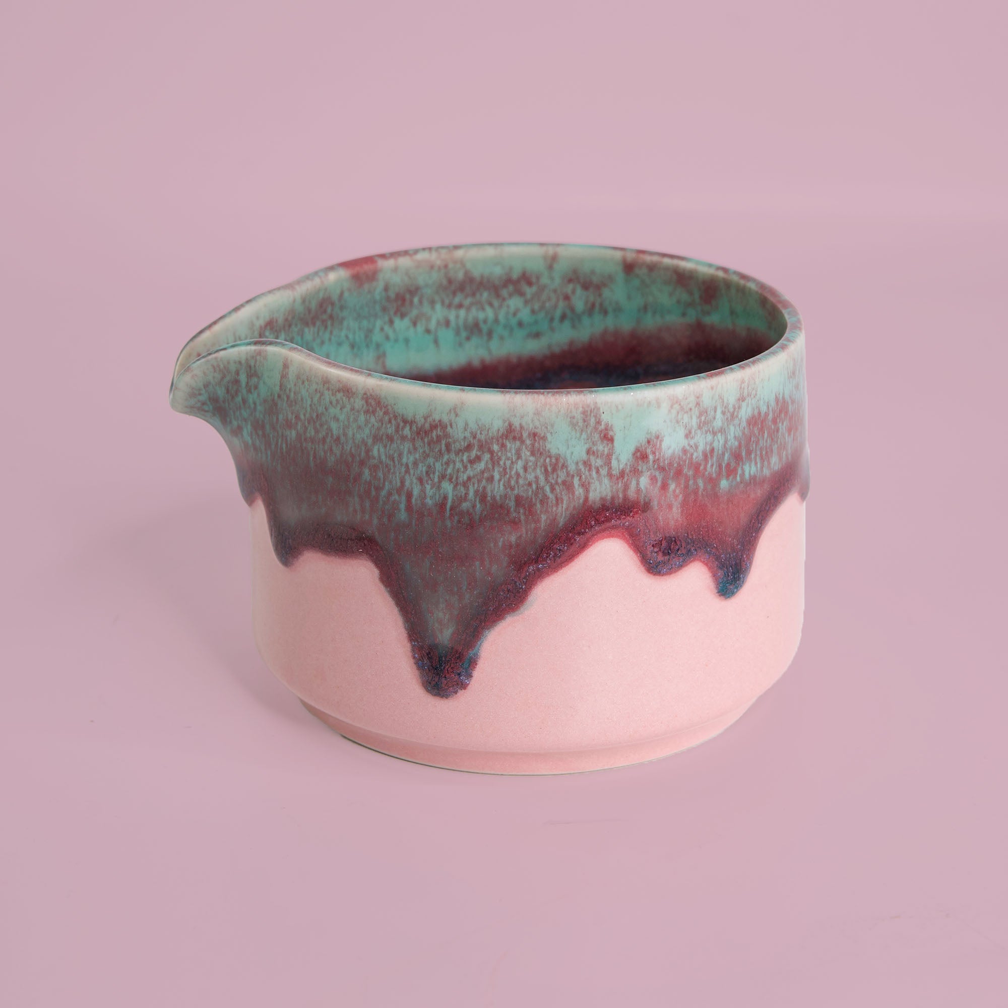 Handcrafted matcha bowl with pink base and green and purple glaze by Pottery For The Planet