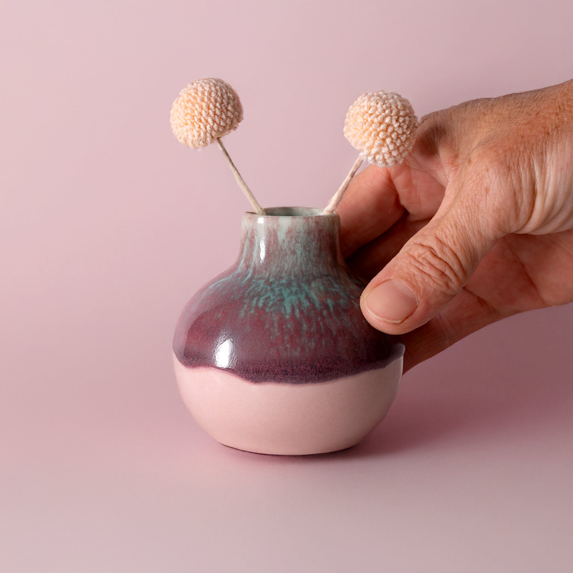 Pottery For The Planet small handmade home decor vase in purple and pink held by hand with dried flowers