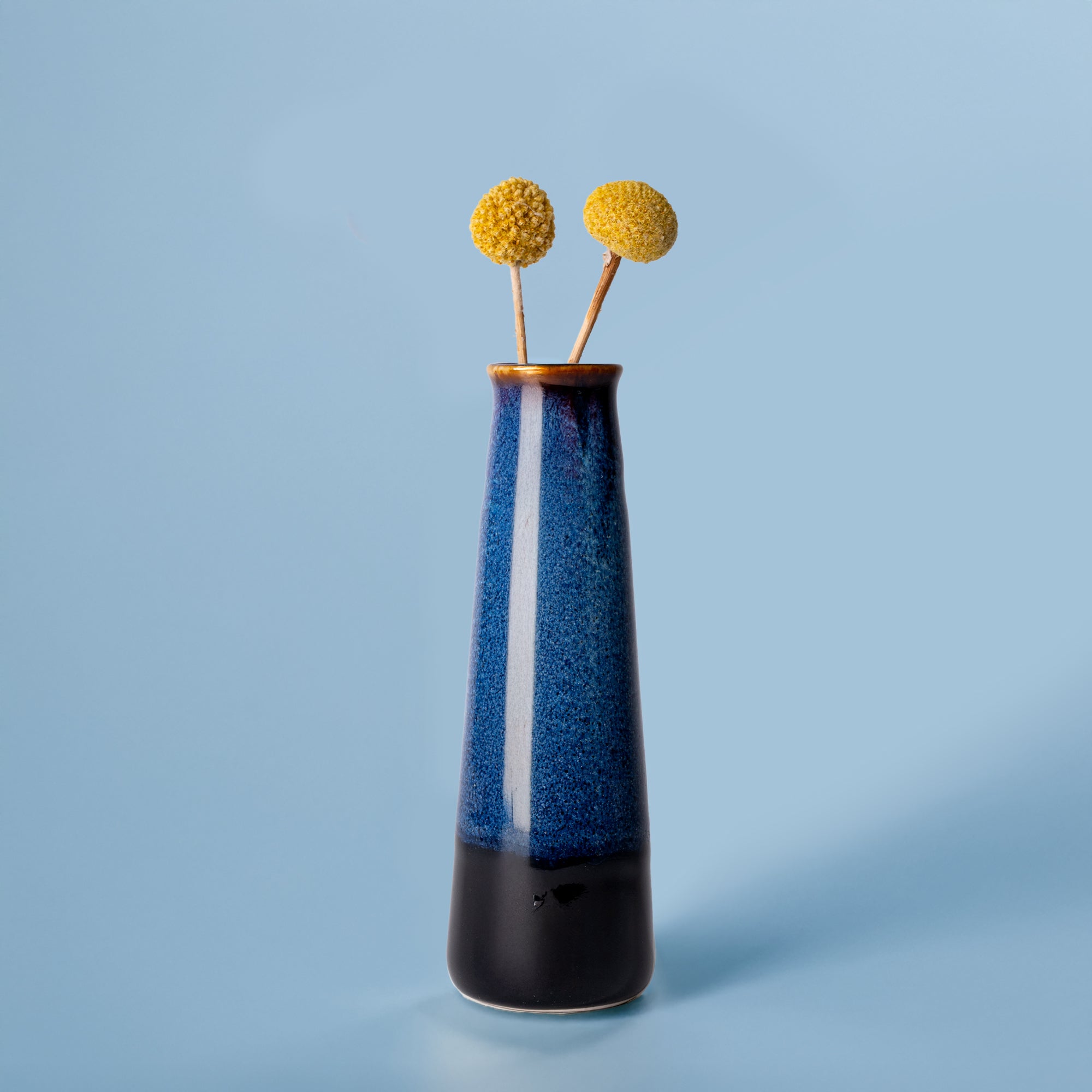 Pottery For The Planet tall blue and black sustainable home decor vase with dried yellow flowers