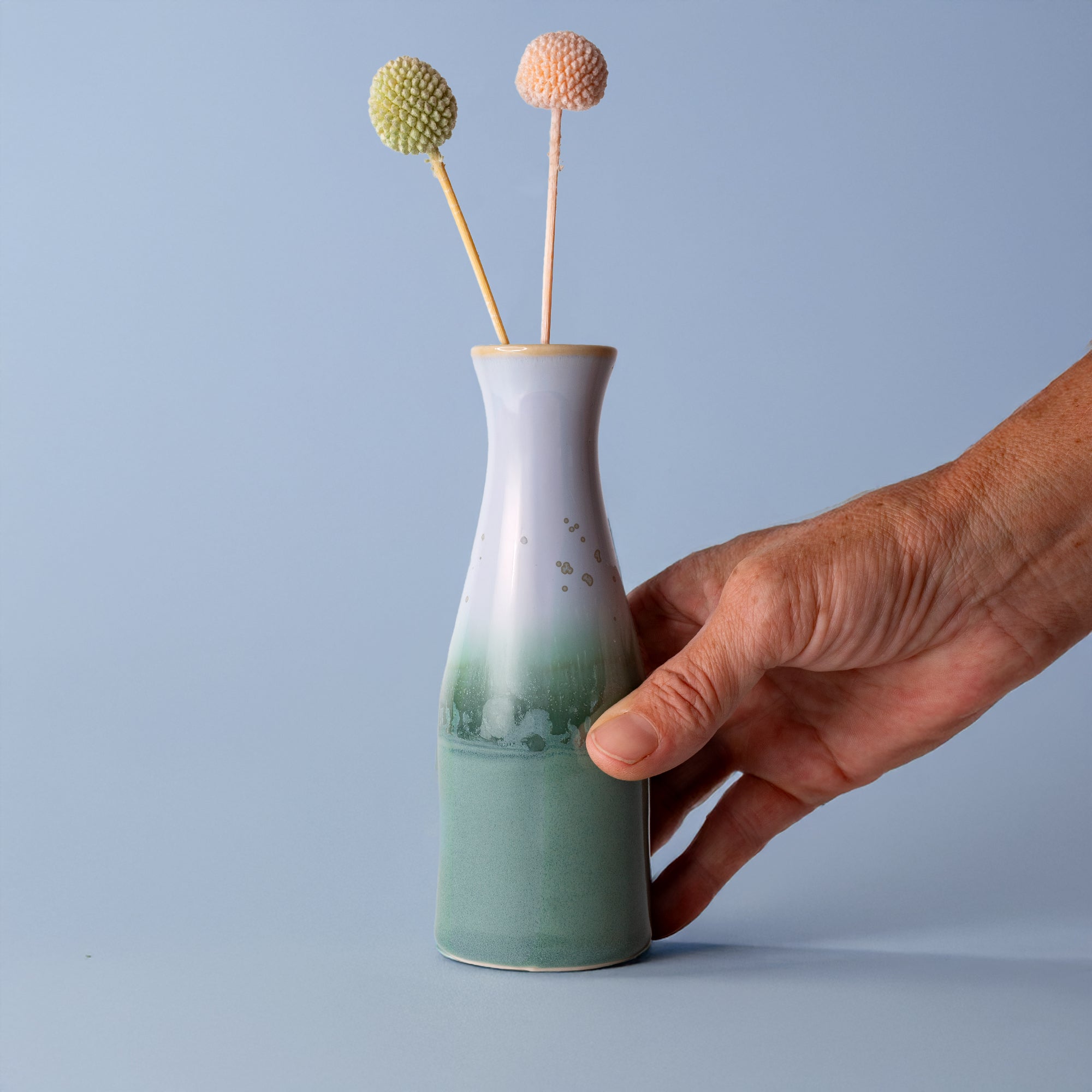 Hand holding unique ceramic flower vase with green and white gradient by Pottery For The Planet
