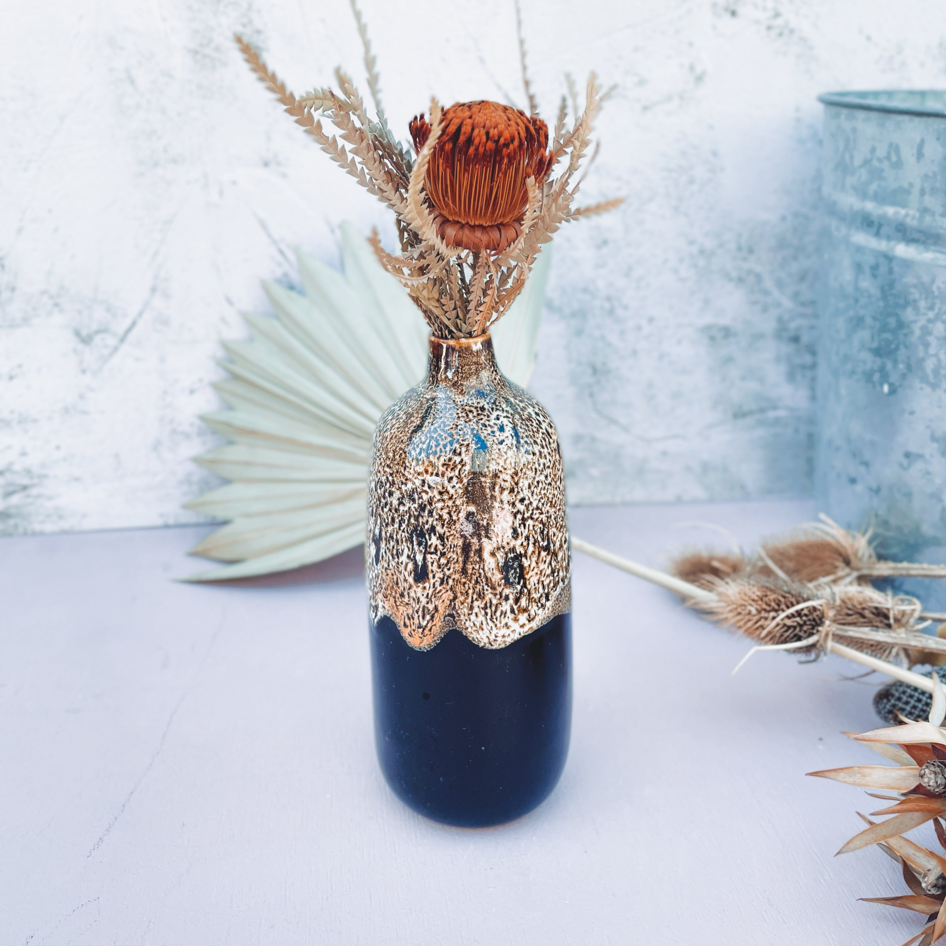 Pottery For The Planet eco-friendly home decor vase with black and metallic finish holding dried flowers